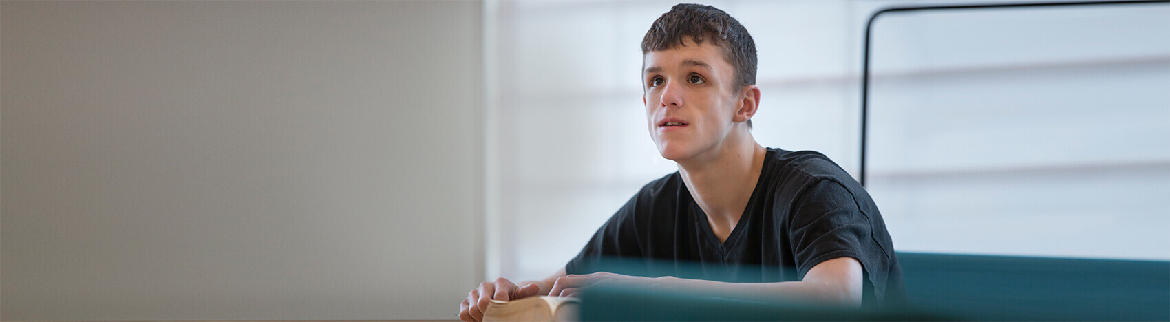Young man with GL sitting on his bed and looking away from the camera